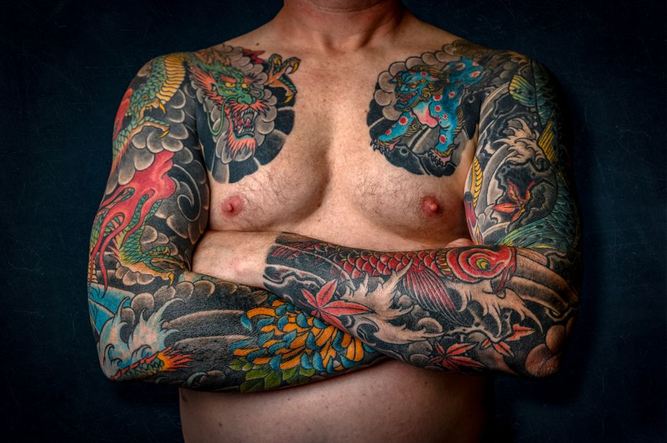 A vibrant neo-traditional color tattoo of the two volcanoes with Aztec calendar patterns and marigold flowers framing the design.